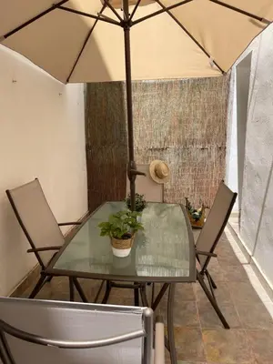 a glass table with two chairs and an umbrella at UIM Mediterraneo PB America Wifi in Puerto de Sagunto