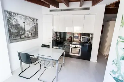 a kitchen with white cabinets and a white table and chairs at Atico Tapineria in Valencia