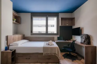 a bedroom with a bed and a desk with a computer at Livensa Living Studios Valencia Marina Real Hotel-Apartamento in Valencia