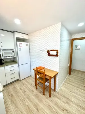 a small kitchen with a table and a refrigerator at Apartamento Ciudamar in Puerto de Sagunto