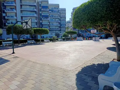 a basketball hoop in a park with a tree and benches at Apartamento Ciudamar in Puerto de Sagunto