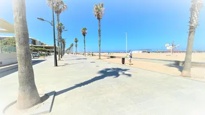a person walking down a sidewalk next to the beach at BEACH VALENCIA LUXURY - B40-21 - Apartament on Beach in Valencia