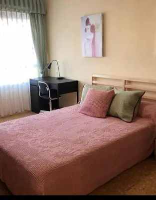 a bedroom with a bed with a desk and a pink blanket at Rooms near the Beach Cabanyal and Universities in Valencia