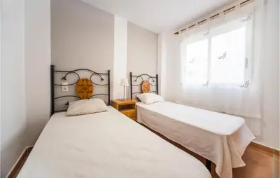 two beds in a room with white walls and a window at 2 Bedroom Pet Friendly Home In Sagunto in Sagunto