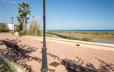 a bench sitting on a sidewalk next to a pole at 2 Bedroom Pet Friendly Home In Sagunto in Sagunto