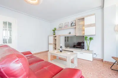 a living room with a red leather couch and a table at Apartamento Familiar en Avenida del Puerto in Valencia