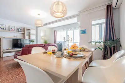 a dining room and living room with a table and chairs at Apartamento Familiar en Avenida del Puerto in Valencia