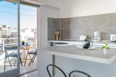 a kitchen with a counter and chairs and a balcony at Town center Apartment El Perello Valencia in El Perelló