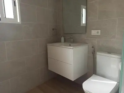 a bathroom with a toilet and a sink and a mirror at Casa cerca de la playa con patio y garaje privado in Puerto de Sagunto