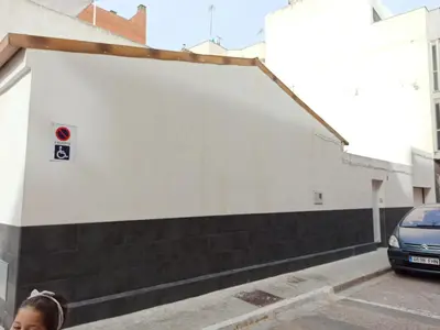a woman walking down a street next to a white building at Casa cerca de la playa con patio y garaje privado in Puerto de Sagunto
