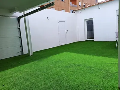 an empty patio with green grass in a building at Casa cerca de la playa con patio y garaje privado in Puerto de Sagunto