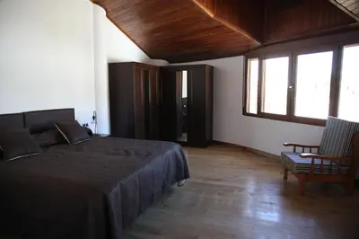 a bedroom with a bed and a chair and windows at Casa Genes Chera in Chera
