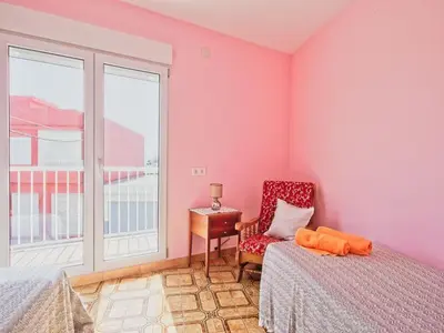 a bedroom with pink walls and a chair and a window at CASA EN LA PLAYA VALENCIA EL PERELLO in Mareny Barraquetas