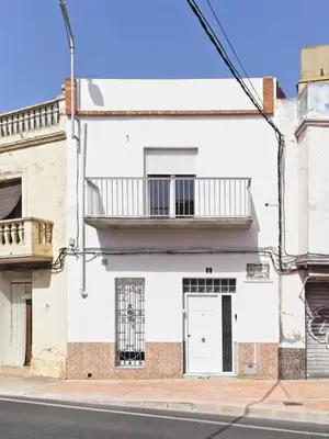 a white building with a door and a balcony at CASA EN LA PLAYA VALENCIA EL PERELLO in Mareny Barraquetas