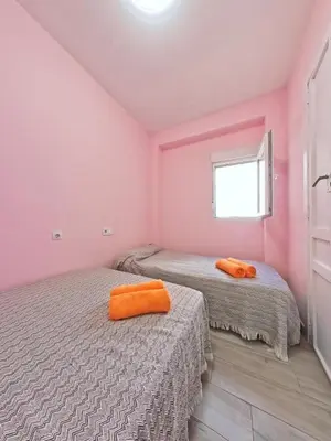 two beds in a pink room with two orange towels at CASA EN LA PLAYA VALENCIA EL PERELLO in Mareny Barraquetas