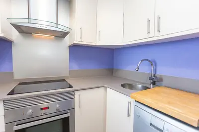 a kitchen with white cabinets and a sink at Cullera Apartment Faro in Cullera