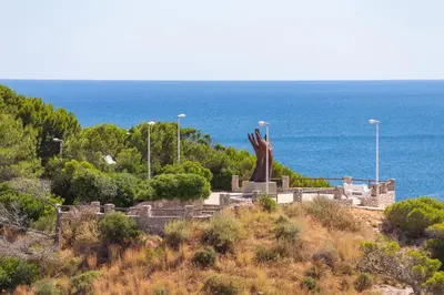a statue on top of a hill near the ocean at Cullera Apartment Faro in Cullera