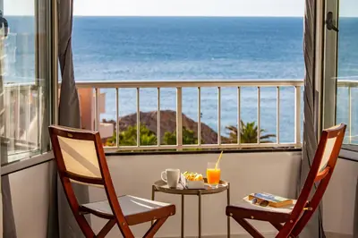 a balcony with two chairs and a table with a view of the ocean at Cullera Apartment Faro in Cullera