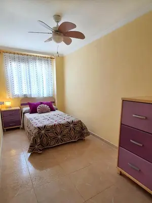 a bedroom with a bed and a ceiling fan at Piso familiar con amplia terraza 300m de la playa in Cullera