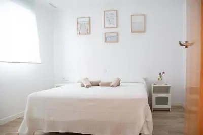 a white bedroom with a bed with a white blanket at Jamaica Beach House in Puebla de Farnals