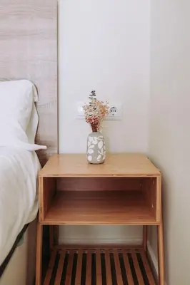 a wooden nightstand with a vase of flowers on it at Estelles D Apartment Close To Beach in Valencia