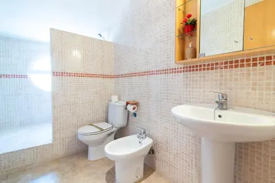 a bathroom with a sink and a toilet and a mirror at Global Vacacional, Adosado en primera linea de playa con vistas al mar in Sagunto