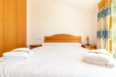 a bedroom with two beds with white sheets and towels at Global Vacacional, Adosado en primera linea de playa con vistas al mar in Sagunto