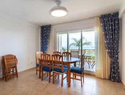 a dining room with a table and chairs and a window at Global Vacacional, Adosado en primera linea de playa con vistas al mar in Sagunto