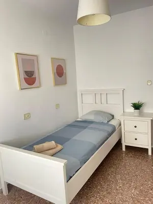 a bedroom with a white bed and a night stand at UIM Mediterraneo Isabel 23 Wifi in Puerto de Sagunto