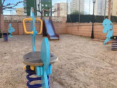 a playground with two slides and a play equipment at Coqueto Apartamento de Playa con Piscina y Terraza in Valencia