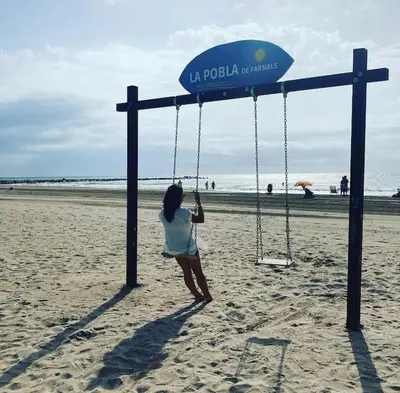 a woman sitting on a swing on the beach at Coqueto Apartamento de Playa con Piscina y Terraza in Valencia