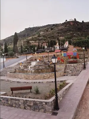 a park with a fountain and a bench and a hill at Apartamentos Rurales San Juan in Castellnovo