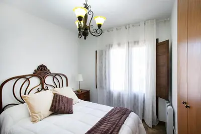a bedroom with a large white bed with a chandelier at Torre Buen Aire cerca de Valencia, con jacuzzi y barbacoa in Benafer