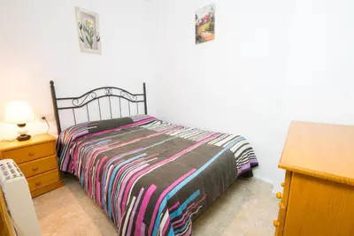 a bedroom with a bed with a striped bedspread and a dresser at El Maestro in Caudiel