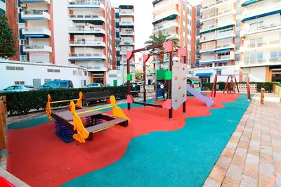 a playground with slides and play equipment on a red carpet at Global Vacacional, Bonito apartamento en Urbanización Ciudad Mar in Puerto de Sagunto
