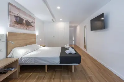 a bedroom with a bed and a tv on a wall at Travel Habitat Alameda Suites. in Valencia