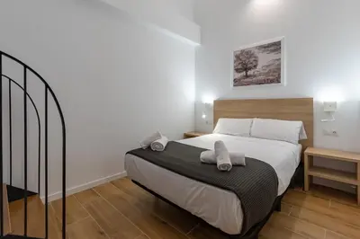 a bedroom with a large bed with white sheets at Travel Habitat Alameda Suites. in Valencia