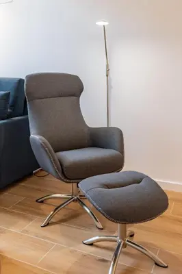 a chair sitting in a living room next to a couch at Travel Habitat Alameda Suites. in Valencia