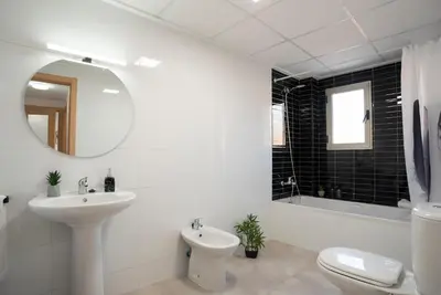 a bathroom with a sink and a toilet and a mirror at Nuevo y moderno apartamento con aire acondicionado - El Cid 4 in Burriana
