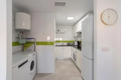 a kitchen with white appliances and a clock on the wall at Nuevo y moderno apartamento con aire acondicionado - El Cid 4 in Burriana