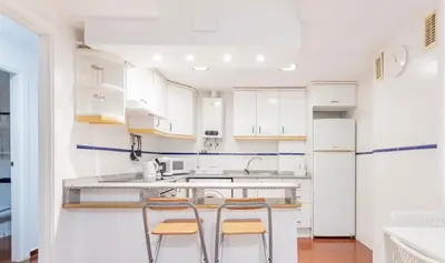 a kitchen with white cabinets and two bar stools at Apartamento Centro Histórico Valencia de 2 habitaciones in Valencia
