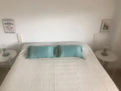 a white bed with two tables in a bedroom at Cullera - Florazar II con piscina, tenis y club social in Cullera