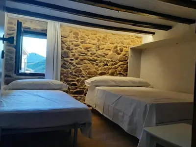 two beds in a room with a stone wall at Casa rural rústica 