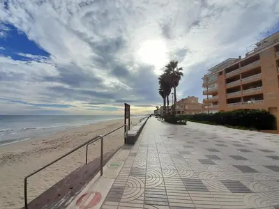 a walkway to the beach with a building and palm trees at Relax Les Palmeres in Sueca
