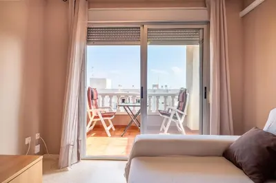 a living room with a couch and a view of a balcony at Global Vacacional, apartamento cerca del mar en Canet in Canet de Berenguer