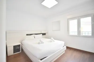 a white bedroom with a large white bed and a window at Gran piso en barrio historico del centro in Valencia