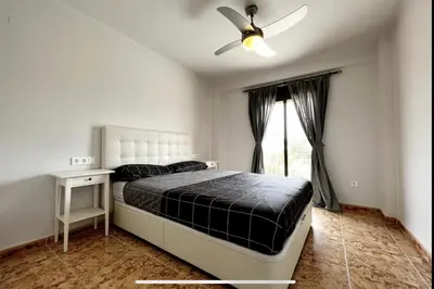 a bedroom with a bed with a ceiling fan and a window at Beach Retreat in Valencia