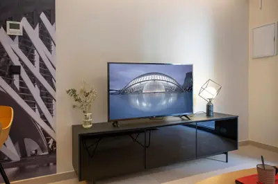 a flat screen tv sitting on a stand in a room at Neobeds - Stylish modern 1BR Apt Near Old Town & Steps from Turia Park in Valencia