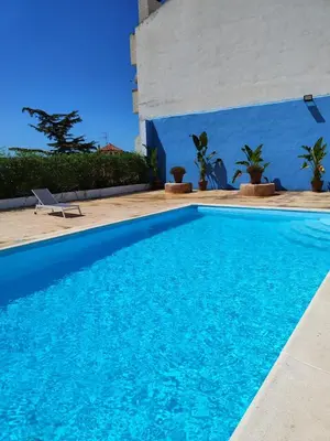 a swimming pool in front of a house with a blue wall at El Recreo, private Pool & Bbq in Godelleta
