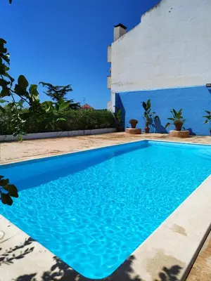 a blue swimming pool in front of a white building at El Recreo, private Pool & Bbq in Godelleta